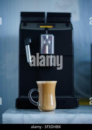 Automatische Kaffeemaschine brüht frischen Kaffee in eine Glas Tasse in einer modernen Küche. Heiße hausgemachte Kaffeebereitung. Stockfoto