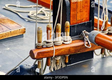 Holzschlingen, die ordentlich aufgerollte Seile auf einem Bootsdeck halten, betonen Segeltradition und Handwerkskunst Stockfoto
