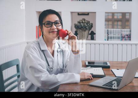 Ärztin mit einem roten Herzball im Krankenhaus. Konzept der Gesundheitsversorgung und Medizin. Stockfoto