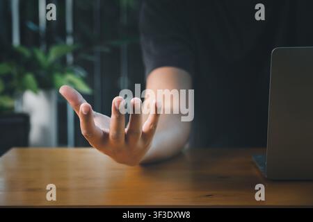 Männliche leere Hand mit geöffneter Handfläche nach oben über einem Laptop auf dem Schreibtisch. Geschäftstechnologie-Konzept. Stockfoto
