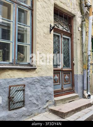 Tallinn, Estland: Verschnörkelte Holztür mit schmiedeeisernen Verzierungen und Vintage-Fenster in der Altstadt. Stockfoto
