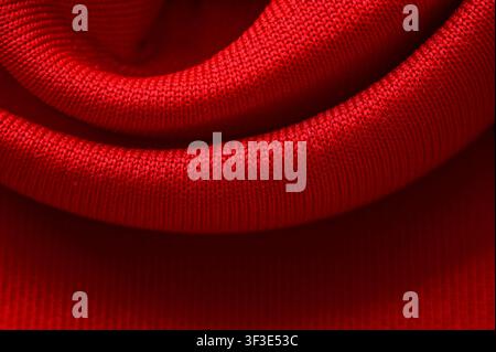 Nahaufnahme von rotem Strickstoff mit weichen Falten und texturierter Textile Oberfläche. Stockfoto