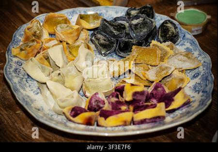 Handgefertigte bunte italienische Nudeln mit Füllung Auswahl an Tortellini und Ravioli auf einem Vintage-Teller Stockfoto