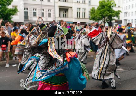 Berlin, Deutschland – 24. Mai 2026. Eine Darstellerin in einem türkisfarbenen Kostüm gesellt sich zu Tänzern in geometrisch gemusterten Gewändern während des Karneval der Kulturen pa Stockfoto