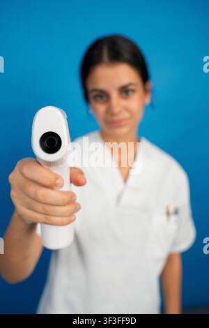 Krankenschwester hält ein kontaktloses Thermometer zur Fieberüberwachung und Krankheitsprävention Stockfoto