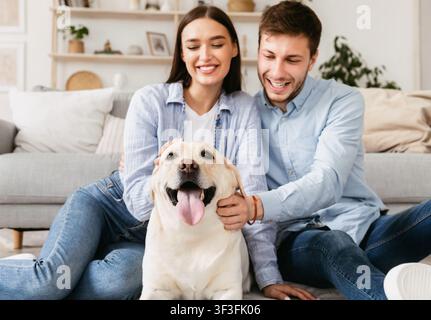 Junge glückliche Paar auf dem Boden mit ihrem Welpen sitzen Stockfoto