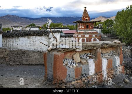 Buddhistische Stupa, auch Akkorde, im Vordergrund auf Lehmwand mit buddhistischen Farben rot, weiß, grau gemalt, tsa tsas, kleine buddhistische Votivobjekte mad Stockfoto