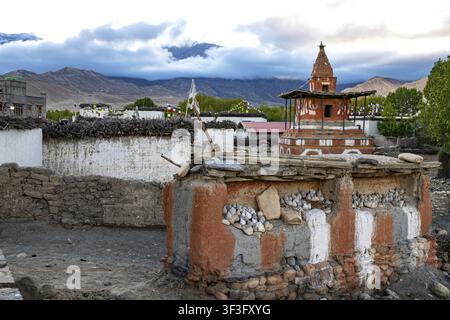 Buddhistische Stupa, auch Akkorde, im Vordergrund auf Lehmwand mit buddhistischen Farben rot, weiß, grau gemalt, tsa tsas, kleine buddhistische Votivobjekte mad Stockfoto