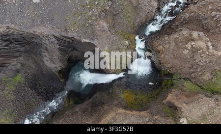 Luftaufnahme des Litlanesfoss-Wasserfalls, der über dramatische Basaltkolonnen in einer rauen vulkanischen Landschaft in Island stürzt. Stockfoto