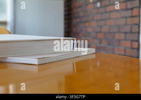 Leere Hardcover-Bücher gestapelt auf Holztablett mit Kopierplatz in modernem Interieur Stockfoto