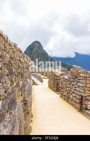 Blick auf die alten Steinmauern und Wege der historischen Inka-Zitadelle von Machu Picchu mit dem hoch aufragenden Berg Huayna Picchu in Machu Picchu, Cu Stockfoto