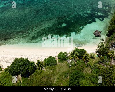 Abgeschiedene Strandbucht mit klarem türkisfarbenem Wasser und felsiger Küstenlinie. Camotes, Philippinen. Stockfoto