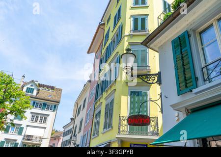 Gelbe historische Gebäudefassade mit grünen Fensterläden und Straßenlaterne in der Altstadt von Zürich, Schweiz. Schmale Gasse in der Altstadt-Hausarchitektur. Fensterladen. Zürich, Schweiz - 23. Juni 2026 Stockfoto