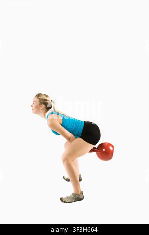 Frau bereitet einen kraftvollen Kettlebell-Schwingzug mit kontrollierter Dynamik vor Stockfoto