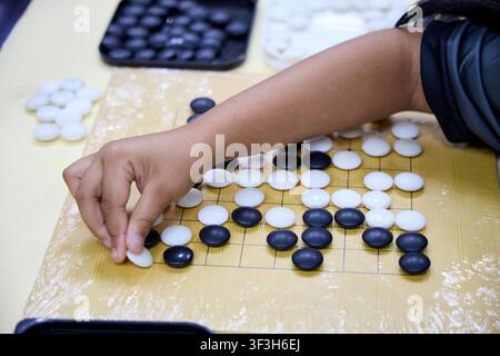 Kinder spielen Go-Brettspiel mit schwarzen und weißen Steinen Stockfoto