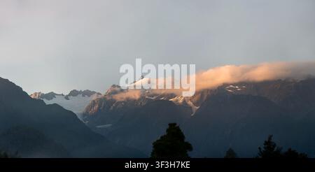 Die Southern Alps umgeben den Franz-Josef-Gletscher bei Sonnenaufgang, gesehen vom Franz Josef TOP 10 Holiday Park, Südinsel, Neuseeland Stockfoto