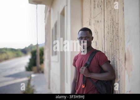 Junger schwarzer Mann mit einem Rucksack lächelt im Freien Stockfoto