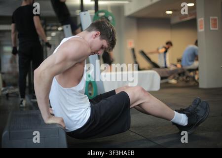 Muskulöser junger Mann macht Trizeps-Dips in einem Fitnessstudio Stockfoto