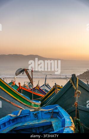 Farbenfrohe Fischerboote, die am Strand von Imsouane in Marokko bei Sonnenuntergang vertäut sind Stockfoto