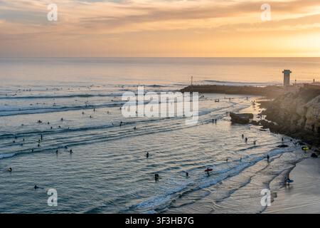 Surfer, die in der Bucht von Imsouane bei Sonnenuntergang in Marokko Wellen reiten Stockfoto