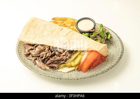 Beef-Shawarma-Wrap mit Tomate, Gurken und Petersilien-Zwiebel-Salat, offen serviert mit Pommes und einem cremigen Dip. Stockfoto