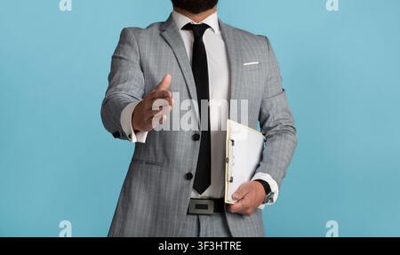 Nahaufnahme eines Geschäftsmannes, der seine Hand ausstreckte, um auf blauem Hintergrund zu zittern Stockfoto