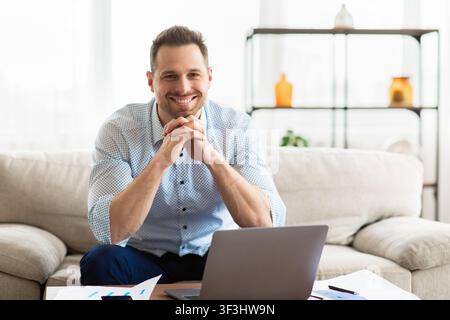 Erwachsener Mann, der auf der Couch sitzt und die Kamera anschaut Stockfoto