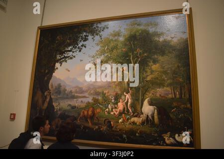 Ein großes klassisches Ölgemälde, das den Garten Eden mit Adam, Eva und verschiedenen Tieren darstellt, hängt in einer Museumsgalerie. Stockfoto