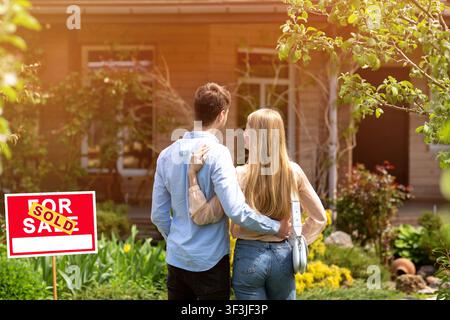 Rückansicht des jungen Paares, das draußen vor dem Hof ihres neuen Hauses steht Stockfoto