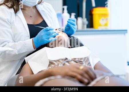 Zahnarzt in weißem Kittel und Handschuhen untersucht die Zähne eines Patienten in einer Klinik Stockfoto