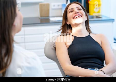 Junge Frau lächelt während eines Zahnarzttermins bei einer Zahnärztin Stockfoto