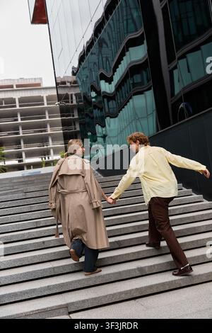 Elegantes junges Paar geht Hand in Hand die modernen Stufen hinauf, in Herbstmode gekleidet Stockfoto