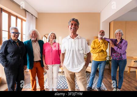Gruppe glücklicher multikultureller Senioren, die Freundschaft, Gemeinschaft und Vitalität genießen, während sie zu Hause stehen und lächeln, was aktives Altern widerspiegelt und Stockfoto