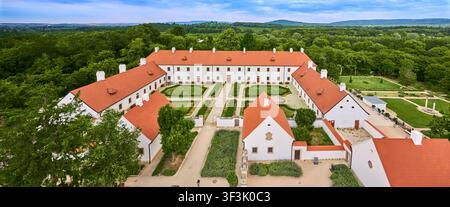 Luftbild des historischen Majk-Klosterkomplexes mit weißen Gebäuden mit roten Dächern und gepflegten Gärten, umgeben von üppigem Wald Stockfoto