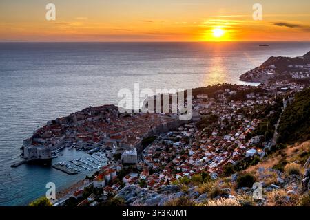 Die zum UNESCO-Weltkulturerbe zählende Altstadt von Dubrovnik wird vom Berg Srđ aus in einer atemberaubenden Luftperspektive gezeigt, die die gesamte ummauerte Stadt im goldenen Sonnenlicht erstrahlen lässt Stockfoto