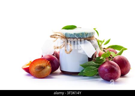 Hausgemachte Pflaumensauce in einem Glas mit reifen Früchten auf weißem Hintergrund. Stockfoto