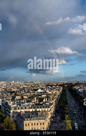 Ein lebendiger Regenbogen wölbt sich über das Dachpanorama von Paris, wie es von der Spitze des Arc de Triomphe aus zu sehen ist, wobei klassische Haussmann-Boulevards ausstrahlen Stockfoto