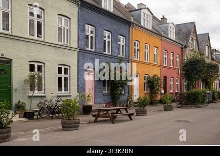 Ansicht von farbenfrohen historischen Häusern mit Fahrrädern und einem hölzernen Picknicktisch in einer ruhigen Straße in Kopenhagen, Dänemark. Stockfoto