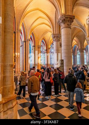 Menschen gehen durch das Hauptschiff der Kathedrale Notre-Dame de Paris unter neu restaurierten Gewölbedecken in Paris, Frankreich Stockfoto