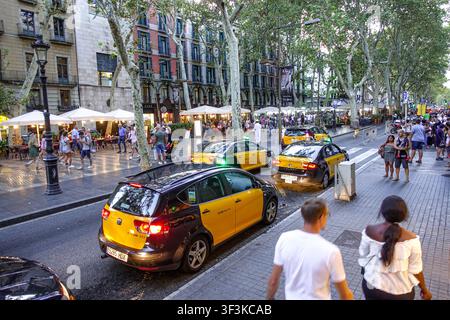 Barcelona, Spanien – 16. August 2018: Blick auf die belebte Straße La Rambla mit gelben und schwarzen Taxis, Fußgängern auf dem Gehweg und Außenbereichen von Restaurants Stockfoto