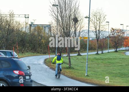 Tromsø, Norwegen - 24. Juli 2026: Blick auf einen Radfahrer, der auf einem gepflasterten Weg in der Nähe von geparkten Autos in einer städtischen Umgebung fährt. Stockfoto