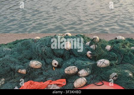 Handelsfangnetze mit Schwimmwaden, die auf einem Hafenpier in Fujairah gestapelt sind, spiegeln die traditionelle Fischereiindustrie und die maritime Wirtschaft der VAE wider Stockfoto