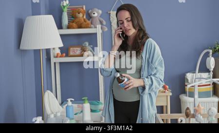 Frau am Telefon hält eine Medicineflasche neben dem Kinderbett im Kinderzimmer, überprüft das Etikett, während sie am Wickeltisch steht; Sorge sucht Hilfe. Stockfoto