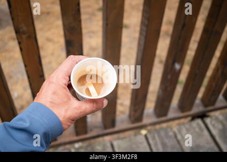 Lässiges Lifestyle-Bild, das eine Hand zeigt, die von oben eine To-go-Kaffeetasse greift Stockfoto