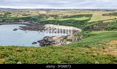 Porth Wen stillgelegte Ziegelei mit Reihen von Windturbinen im Hintergrund an der Küste in Anglesey, Wales am 20. Juli 2026 Stockfoto