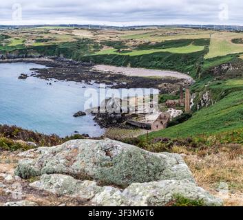 Porth Wen stillgelegte Ziegelei mit Reihen von Windturbinen im Hintergrund an der Küste in Anglesey, Wales am 20. Juli 2026 Stockfoto