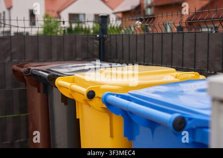 Hausmülltonnen für verschiedene Arten von recycelbaren Materialien stehen im Außenbereich des Sammelplatzes. Konzept des Abfallmanagements und des Recyclings Stockfoto