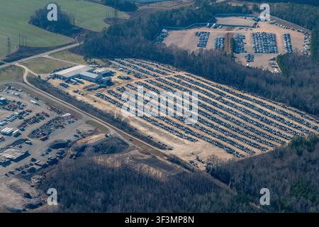Luftaufnahme eines Autoverwertungshofs in der Nähe von Charles City, Virginia. Reihen von Fahrzeugen sind ordentlich in einem weiten offenen Bereich aufgereiht, der von dichtem Wald umgeben ist Stockfoto