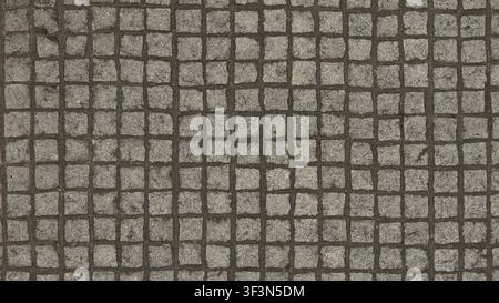 Eine Nahaufnahme von quadratischen grauen Granitpflastersteinen, die in einem Rastermuster auf einer Straße verlegt sind. Stockfoto