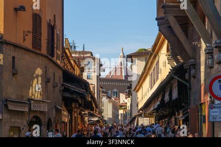 Florenz, Toskana, Italien. 28. Mai 2026. - Eine überfüllte historische Straße in Florenz, Italien, in warmem goldenem Licht gebadet, die auf den ikonischen Bogen zuführt Stockfoto